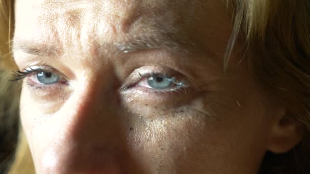 Slow motion close up: Tear comes out of an eye and streaks down the cheek. Sad female with blue painted eyes crying — Stock Video