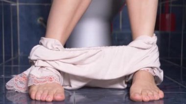 onun midesinde bir acıyla tuvalette oturan bir adamın ayakları. 4 k, yakın çekim, kadın tuvalette pijama
