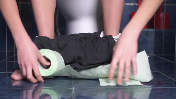 Los pies de un hombre que se sienta en el inodoro con un dolor en el estómago. 4k, primer plano, chico adolescente en pantalones cortos en el inodoro . — Vídeos de Stock
