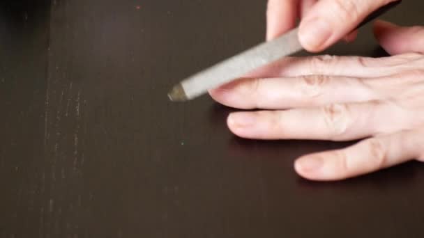 Maniküre Nägel lackieren. Eine Frau sägt ihre Nägel auf einem dunklen Holztisch ab. 4k, Nahaufnahme, Zeitlupe — Stockvideo