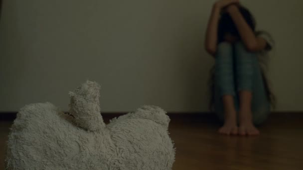 うつ病の絶望的な子は、自殺しようとする彼の部屋の壁に座っています。隣には、放棄された柔らかいおもちゃです。4 k、スローモーション. — ストック動画