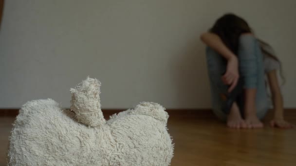 Zoufalé dítě v deprese sedí na zdi svého pokoje, snaží se pokusí o sebevraždu. vedle něj je opuštěné Plyšová hračka. 4k, pomalý pohyb. — Stock video