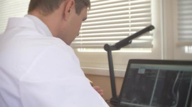 Doktor, hasta MRI makinesinde hareket ederken bilgisayar ekranına bakarak doktor onun laptop manyetik rezonans görüntüleme sonuçlarını analiz eder. 4k, arka plan bulanıklık