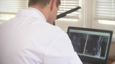Doktor, hasta MRI makinesinde hareket ederken bilgisayar ekranına bakarak doktor onun laptop manyetik rezonans görüntüleme sonuçlarını analiz eder. 4k, arka plan bulanıklık