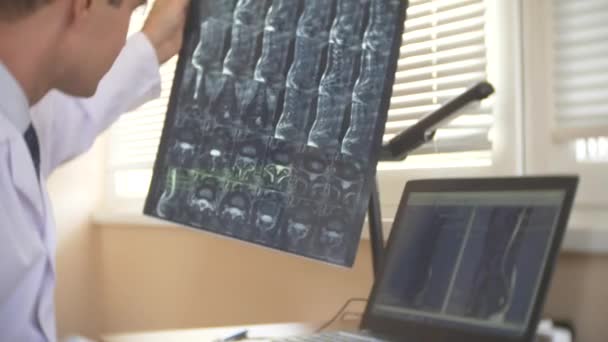 Lekarz ogląda ekranu komputera podczas przemieszczania pacjenta w maszyny mri, lekarz przeanalizuje wyniki rezonansu magnetycznego na swoim laptopie. 4k, rozmycie tła — Wideo stockowe