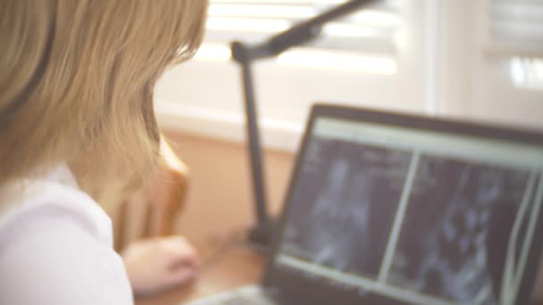 Médico olhando para a tela do computador enquanto o paciente se move na máquina de ressonância magnética, o médico analisa os resultados da ressonância magnética em seu laptop. 4k, borrão de fundo — Vídeo de Stock