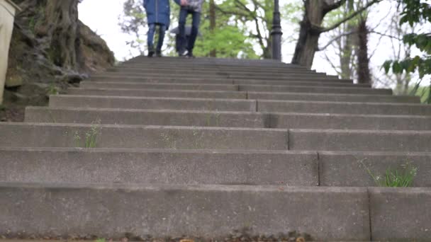 Adolescents, garçon et fille descendent les escaliers, se tenant la main. Gros plan des jambes en chaussures noires, descendant les escaliers, ralenti, prise de vue en angle bas. 4k, au ralenti — Video