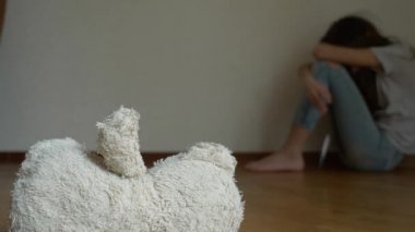 depresyon umutsuz bir çocuk odası duvar oturur, intihar girişimi çalışır. Bu yanındaki terk edilmiş bir yumuşak oyuncak var. 4k, ağır çekim.