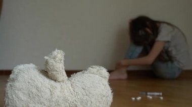 depresyon umutsuz bir çocuk odası duvar oturur, intihar girişimi çalışır. Bu yanındaki terk edilmiş bir yumuşak oyuncak var. 4k, ağır çekim.