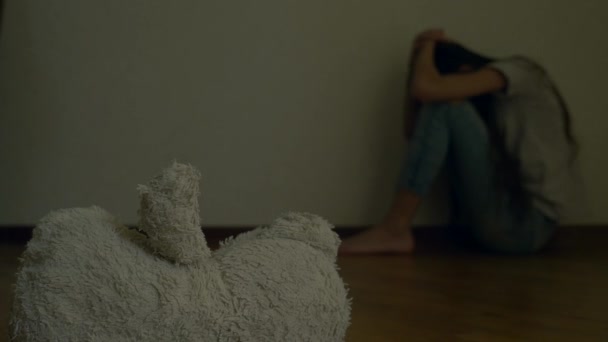 Ein verzweifeltes Kind in Depressionen sitzt an der Wand seines Zimmers und versucht Selbstmord. Daneben steht ein verlassenes Stofftier. 4k, Zeitlupe. — Stockvideo