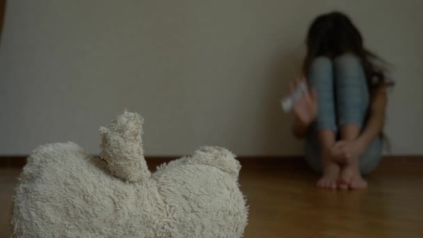 우울증에 절망적 인 아이, 자살 시도 하려고 그의 방의 벽에 앉는 다. 옆은 버려진된 부드러운 장난감입니다. 4 k, 슬로우 모션. — 비디오