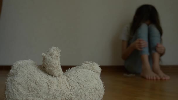 Ein verzweifeltes Kind in Depressionen sitzt an der Wand seines Zimmers und versucht Selbstmord. Daneben steht ein verlassenes Stofftier. 4k, Zeitlupe. — Stockvideo