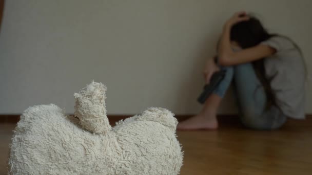 A desperate child in depression sits at the wall of his room, tries to attempt suicide. next to it is an abandoned soft toy. 4k, slow motion. — Stock Video