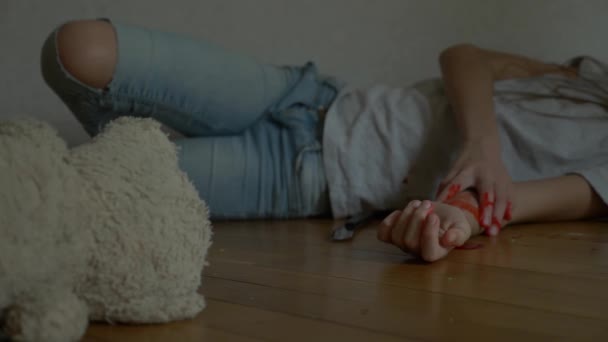 Un niño desesperado en depresión se sienta en la pared de su habitación, intenta suicidarse. junto a ella hay un juguete suave abandonado. 4k, cámara lenta . — Vídeo de stock