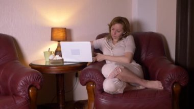 gece laptop çalışma ve yemek kadın aperatifler, koltuk evde oturan. 4k, ağır çekim.