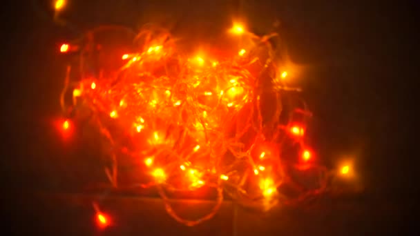 A multi-colored blinking garland lies on the floor. 4k, slow motion — Stock Video