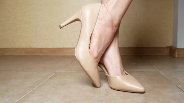 Close-up. pernas femininas em sapatos cremosos de salto alto. dentro de casa. 4k — Vídeo de Stock