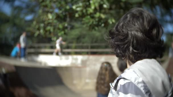 Un niño solo usando un teléfono móvil al aire libre. mientras otros niños descansan activamente. Adicción a teléfonos inteligentes. 4k, cámara lenta — Vídeos de Stock