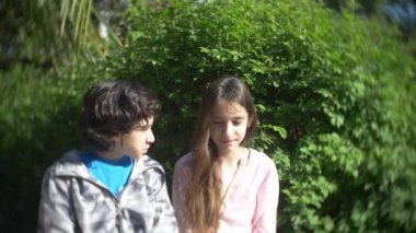 iki sevimli genç erkek ve kız bir çiçeklenme konuşurken park bahar. 4k, ağır çekim
