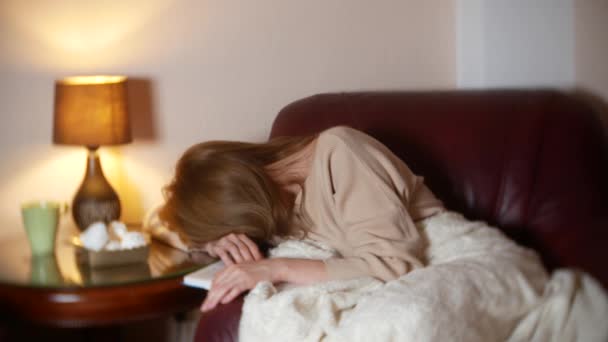 Вночі дівчина читає книгу під ковдрою на стільці. вона засинає читаючи нецікаву нудну книгу 4k , — стокове відео