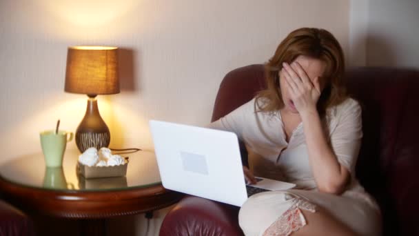 在晚上工作的妇女在膝上型电脑和吃零食, 坐在扶手椅在家。4k、模糊框架边框. — 图库视频影像