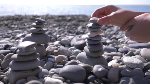 Közeli, a kéz bedobja a piramis kövek a tengerparton. 4k, lassú mozgás — Stock videók