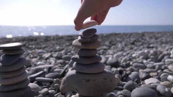 Zbliżenie, ręka fałdy piramida z kamieni na brzegu morza. 4k, zwolnionym tempie — Wideo stockowe