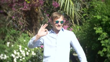 Genç adam giyen güneş gözlüğü açık havada park gündüz güneş ligth 4 k, yavaş hareket, başparmak