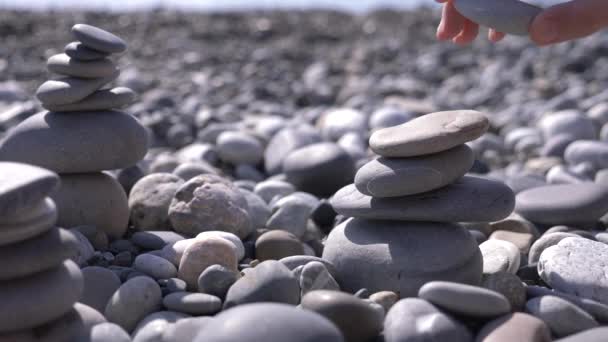 gros plan, main plie une pyramide de pierres sur le bord de la mer. 4k, au ralenti 