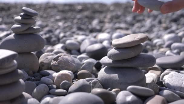 In Großaufnahme faltet die Hand eine Steinpyramide am Meeresufer. 4k, Zeitlupe — Stockvideo