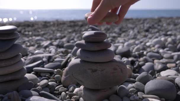 In Großaufnahme faltet die Hand eine Steinpyramide am Meeresufer. 4k, Zeitlupe — Stockvideo