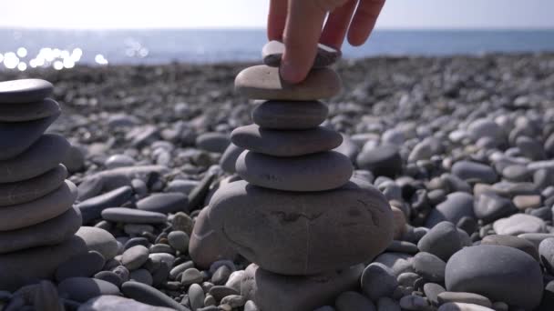 Detail, ruce složí pyramidy kameny na břehu moře. 4k, pomalý pohyb — Stock video