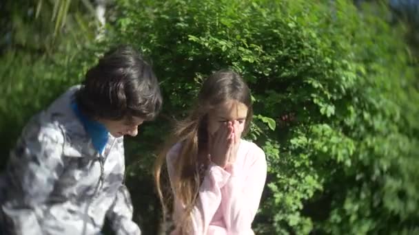 Dos lindo adolescente chico y chica hablando en un floreciente parque de primavera. 4k, cámara lenta — Vídeos de Stock