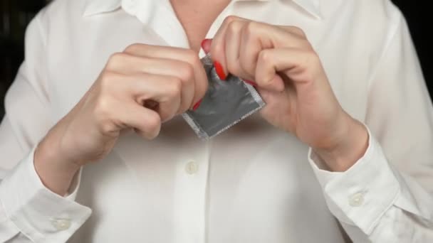 4k, Zeitlupe, Nahaufnahme. Frauenhände versuchen, die Kondompackung zu öffnen. das Konzept von sicherem Sex und Verhütung. — Stockvideo
