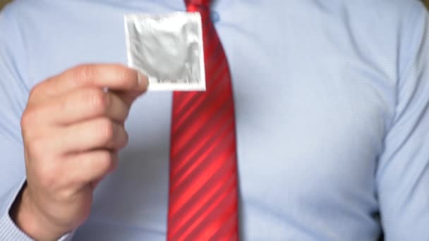 4k, cámara lenta, primer plano. Manos de hombre sostienen un condón empaquetado. El concepto de sexo seguro y anticoncepción . — Vídeo de stock