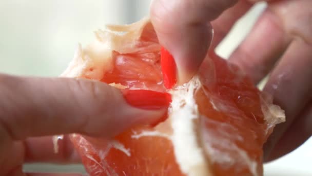 Женские руки очищают грейпфрут. 4k, крупный план, замедленная съемка — стоковое видео