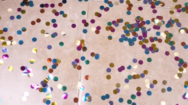 Замедление. 4k. Круглые разноцветные конфетти лежат на плитке пола. Стрельба в кукол — стоковое видео