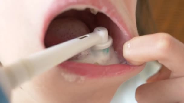 L'enfant nettoie ses dents devant un miroir en 4k. fille adolescent brosse les dents avec brosse à dents électrique, gros plan, tir au ralenti — Video