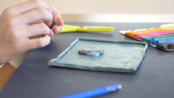 A menina sentada à mesa, desenha figuras diferentes da plasticina de modelo a cores. Desenvolvimento de modelagem de arte em crianças. 4k, close-up, câmera lenta — Vídeo de Stock