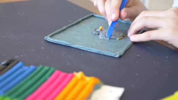 A menina sentada à mesa, desenha figuras diferentes da plasticina de modelo a cores. Desenvolvimento de modelagem de arte em crianças. 4k, close-up, câmera lenta — Vídeo de Stock