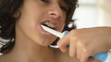 Çocuk 4 k bir ayna önünde dişlerini temizler. çocuk genç elektrikli diş fırçası, yakın çekim, ağır çekim çekim ile diş fırçaları