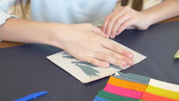 A menina sentada à mesa, desenha figuras diferentes da plasticina de modelo a cores. Desenvolvimento de modelagem de arte em crianças. 4k, close-up, câmera lenta — Vídeo de Stock