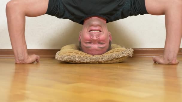 Um homem engraçado faz flexões de cabeça para baixo na casa. 4K, boneca de tiro — Vídeo de Stock