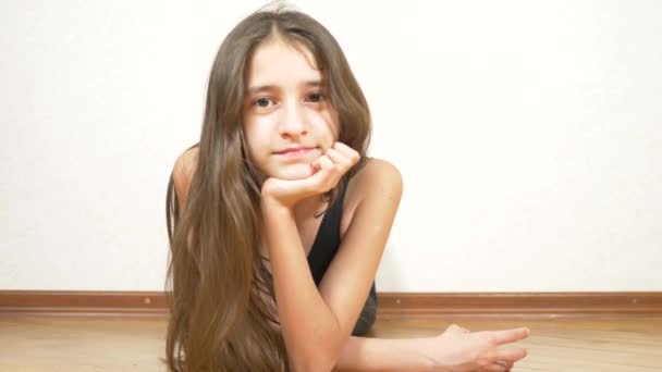 Fata stă întinsă pe podea în sala de gimnastică și zâmbește la cameră, 4k . — Videoclip de stoc