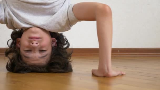 Un adolescente gracioso hace flexiones al revés en la casa. 4k, disparando a Dolly. Movimiento lento — Vídeos de Stock