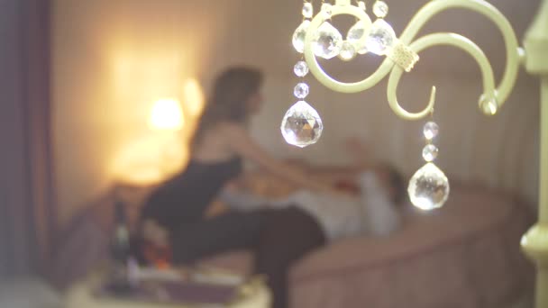Зосередьтеся на круглих кристалах від лампи. Ардент закохана пара сидить на ліжку і обіймається з пристрастю на фоні. Романтична концепція побачень. 4k, розмивання — стокове відео