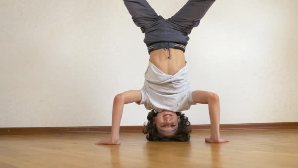 Un adolescente gracioso hace flexiones al revés en la casa. 4k, cámara lenta — Vídeo de stock