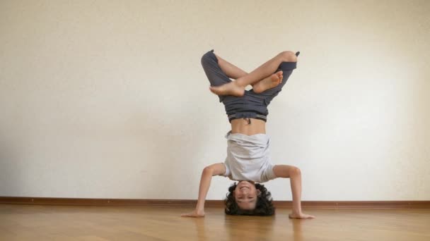 Un adolescente gracioso hace flexiones al revés en la casa. 4k, cámara lenta — Vídeo de stock