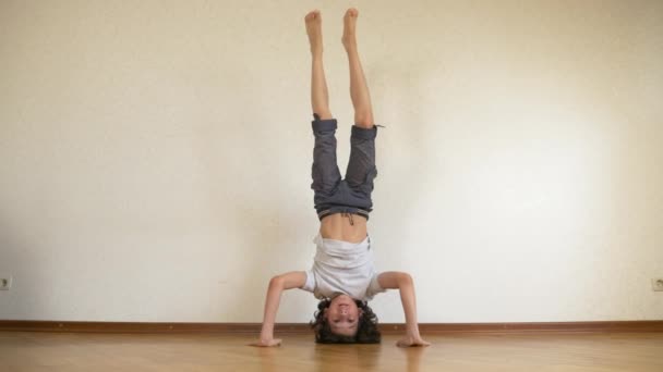 Un adolescente gracioso hace flexiones al revés en la casa. 4k, cámara lenta — Vídeo de stock