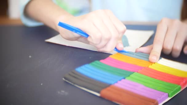 La chica sentada en la mesa, dibuja diferentes figuras de plastilina modelo de color. Desarrollo del modelado artístico en niños. 4k, primer plano — Vídeo de stock